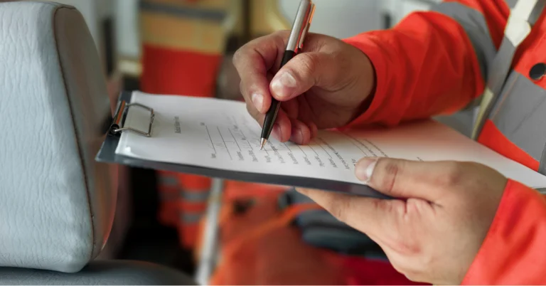 Personne en veste de travail orange remplissant un formulaire sur un porte-bloc