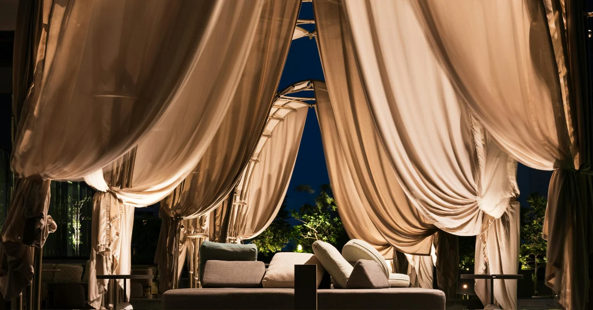 Beige curtains framing an outdoor lounge at night