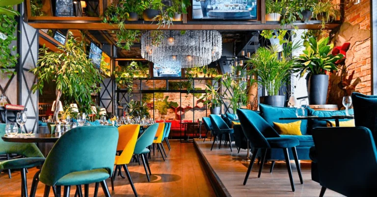 Salle de restaurant aux fauteuils en velours bleu-vert, décorée de plantes